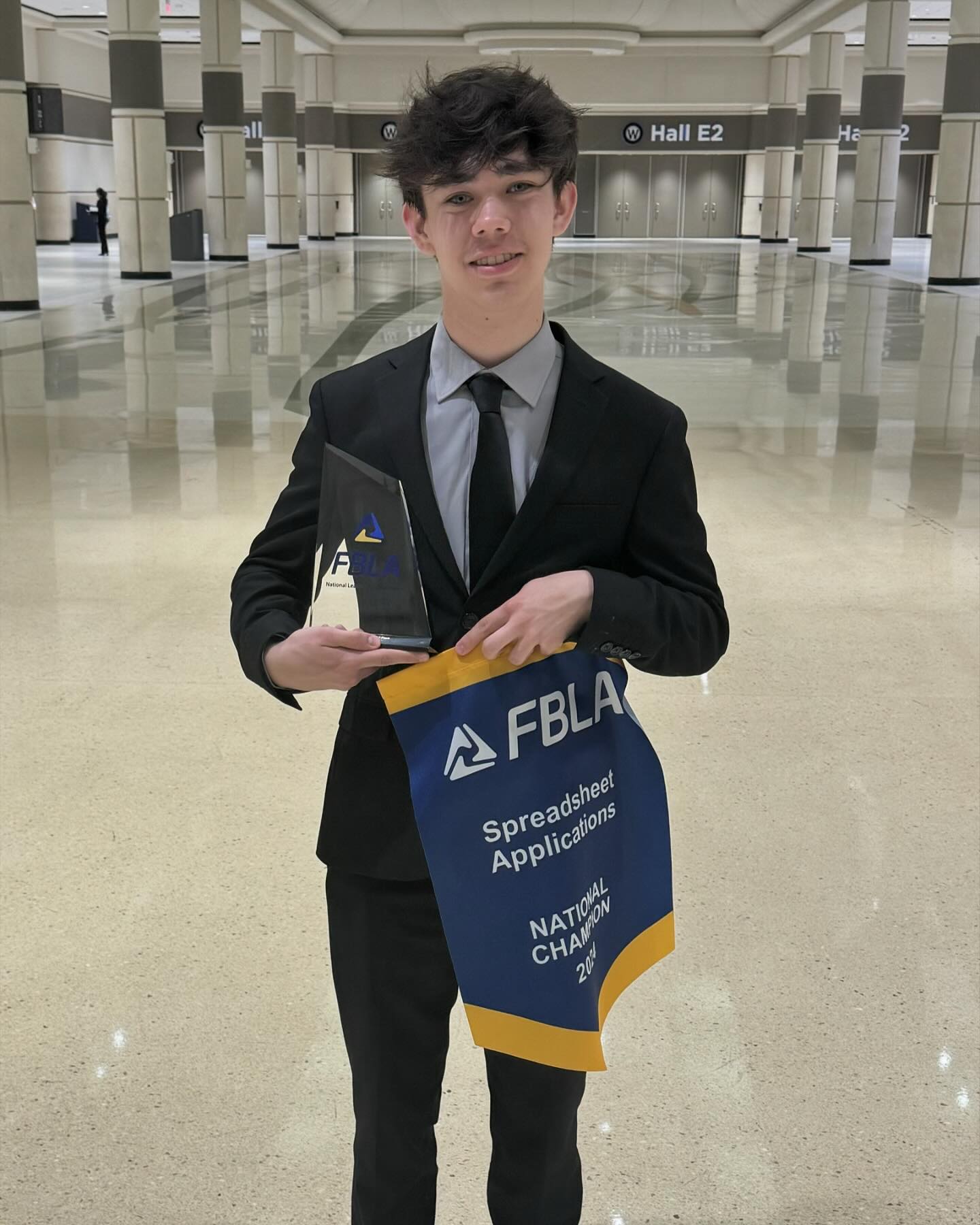 Brayden holding a glass trophy and banner