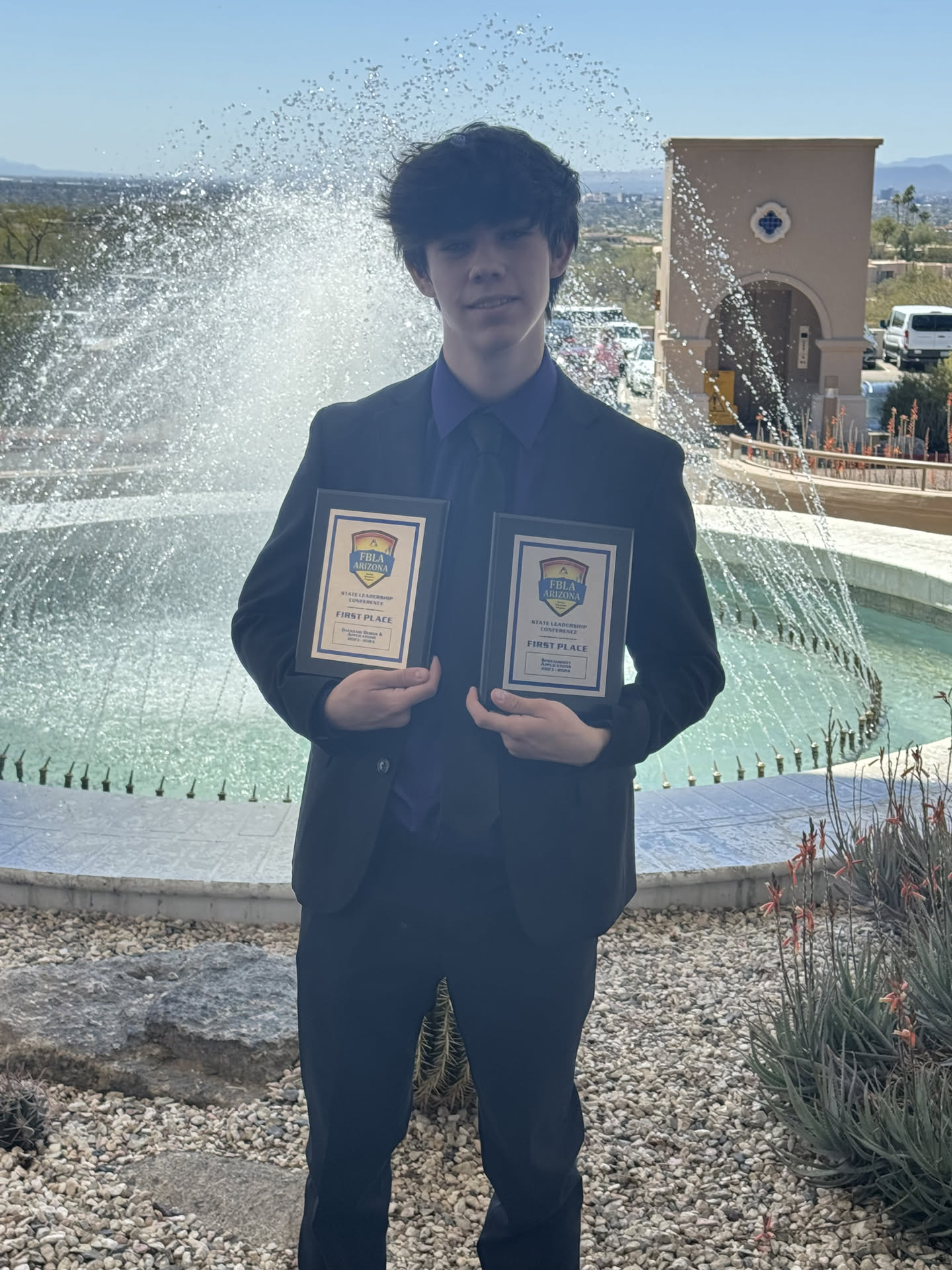 Brayden holding two plaques